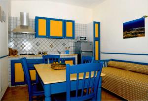 een keuken met blauwe en gele kasten en een tafel en stoelen bij Residence Punta Longa in Favignana