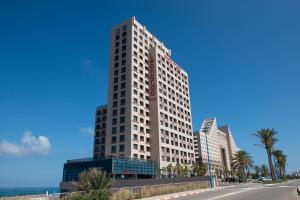 Un alto edificio bianco con un orologio sopra di master Haifa Beach Apartments a Haifa