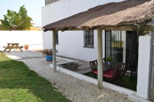 una casa con tetto di paglia, tavolo e tavolo da picnic di Casa "La Breña". Surf,sol y relax. a Los Caños de Meca