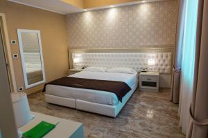 - une chambre avec un grand lit et un miroir dans l'établissement Aurum Suites, à Pescara