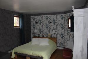 een slaapkamer met een bed met een groene sprei bij Chambres d'hôtes L'Aubaine avec jacuzzi in Wanquetin