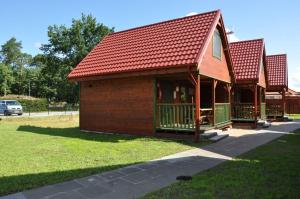 un pequeño edificio con techo rojo en la hierba en Słoneczny Zakątek, en Sztutowo