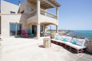 un patio con sofá, sillas y el océano en Maison Ses Covetes, en Ses Covetes