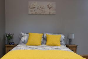 um quarto com uma cama amarela e 2 almofadas amarelas em Little Oak by RentMyHouse em Hereford