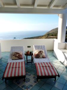 Dos sillas en un balcón con vista al mar. en Casa Tramonto, en Lipari