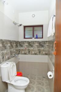 a bathroom with a white toilet and a window at Athrakkattu Enclave in Trivandrum +54 photos