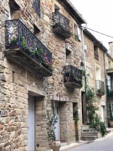 a stone building with balconies and flowers on it at Domaine de Flo in Saint-Jean-de-la-Blaquière