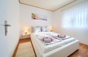 a white bedroom with a large white bed with pink pillows at Apartments Braut Krk in Krk