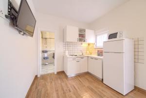 a white kitchen with a refrigerator and a sink at Apartments Braut Krk in Krk