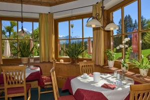 Alpenhotel Hundsreitlehen في بيشوفسفيزن: غرفة طعام مع طاولات وكراسي ونوافذ