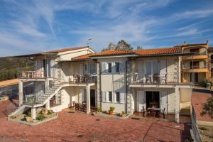 an image of a house with balconies and tables at GF Apartments Li Seddi in Badesi