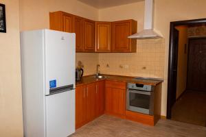 a kitchen with a white refrigerator and wooden cabinets at Kvartirkoff na Petra Kalnyshevsky 7, 26 floor in Kyiv