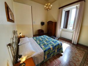 a bedroom with a bed and a window and a chandelier at Albergo Cavour in Palermo