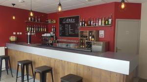un bar con taburetes negros y una pared roja en Le cabistou, en Devesset