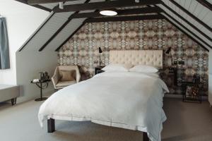 a bedroom with a large white bed and a chair at The Bonnie Badger in Gullane