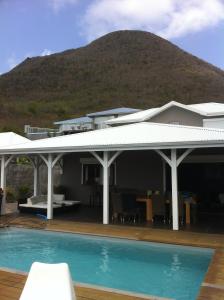 a house with a pool in front of a mountain at Domaine Diamant Caraibes in Le Diamant