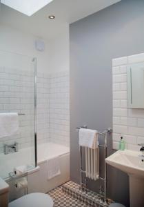 a bathroom with a tub and a toilet and a sink at The Old Post Office - Bright & Modern 4BDR Townhouse in Oxford