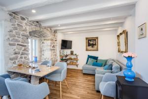 a living room with blue chairs and a stone wall at Water Castle House in Kaštela