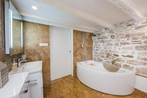 a bathroom with a white tub and a stone wall at Water Castle House in Kaštela +23 photos