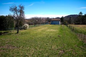 a field with a fence and a house in the distance at Teresita-the Green House in Pisano