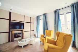 un soggiorno con 2 sedie gialle e una TV di La Balconada de Toledo - PARKING GRATIS - 2 HABITACIONES a Toledo