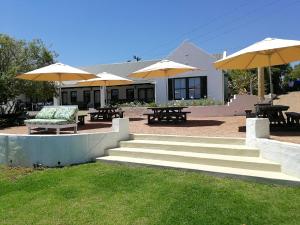 een patio met tafels, stoelen en parasols bij Lady Loch Country House in Wellington