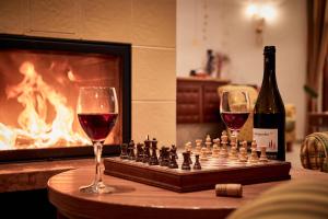 a chess board and two glasses of wine next to a fireplace at Ferienpension Zummüllerhof in Natz-Schabs