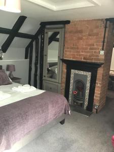 a bedroom with a bed and a brick fireplace at Anglebury House in Wareham