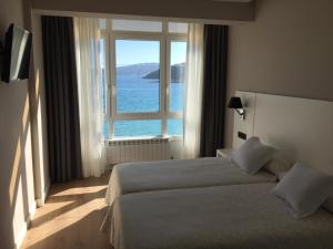a bedroom with a bed and a large window at Hotel La Cruz in Muxia