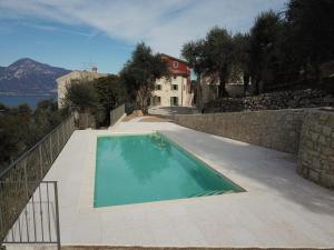 a swimming pool next to a stone wall and a house at Agriturismo Le Anze in Torri del Benaco