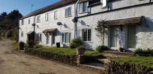 una casa bianca con un muro di pietra di No 4 Trelawney Apartment - Onsite Bar - Restaurant - Horse Riding a Menheniot