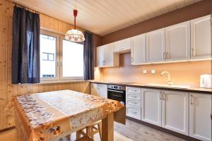 a kitchen with white cabinets and a table at Domek na Zagroniu in Istebna