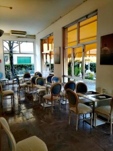 a dining room with chairs and tables and windows at Hotel Giulia in Marina di Massa
