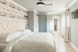 a bedroom with a white bed and a brick wall at The Bonnie Badger in Gullane