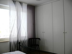 ein Schlafzimmer mit weißen Schränken und einem Stuhl neben einem Fenster in der Unterkunft Ferienwohnung Hudewusch in Bad Harzburg