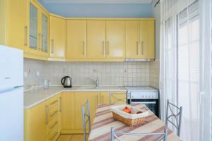 eine Küche mit gelben Schränken und einem Tisch mit einem Obstkorb in der Unterkunft Sunny by the Beach in Chrisi Ammoudia + 7 Fotos