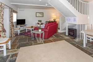 a living room with a red couch and a fireplace at Stable Cottage in Enford