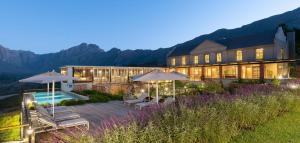a large building with a pool and umbrellas at De Zeven Guest Lodge in Stellenbosch