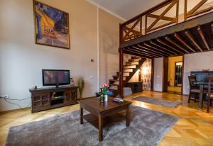a living room with a table and a tv and a staircase at Select City Center Apartments in Braşov