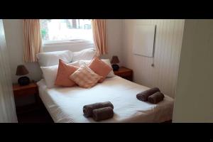 a white bed with two brown towels on it at Woodbourne Resort in Knysna