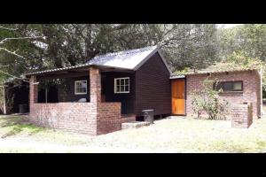 a small brick house with a brick chimney next to a building at Woodbourne Resort in Knysna