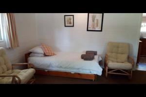 sypialnia z łóżkiem, krzesłem i kanapą w obiekcie Woodbourne Resort w mieście Knysna