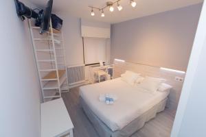 Habitación pequeña con cama blanca y escalera en Hostal Viena, en Soria