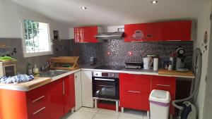 a kitchen with red cabinets and a stove top oven at homedelabaie in Pontorson