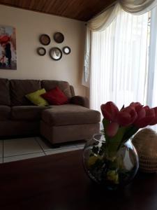 a living room with a couch and a vase of flowers on a table at Kubo Apartment in Alajuela City