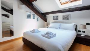 una camera da letto con un letto bianco e asciugamani di Italianway - Baiamonti 1 a Milano