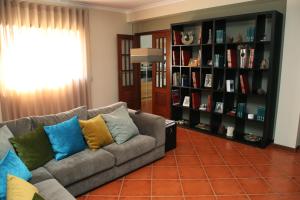 a living room with a couch and shelves of books at Quinta do Pombal Douro in Penajoia