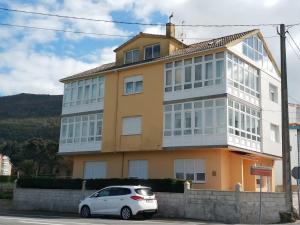 een witte auto geparkeerd voor een gebouw bij Casa Mallou in San Mamede de Carnota