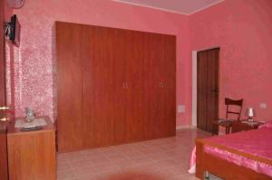 sypialnia z różowymi ścianami i drewnianymi drzwiami w obiekcie B&B Il Gabbiano w mieście SantʼAntìoco