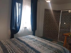 Schlafzimmer mit einem Bett mit blauen Vorhängen und einem Fenster in der Unterkunft Confort By The Sea in Vico Equense